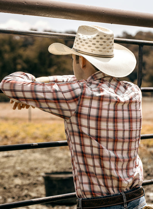 a man in a cowboy hat leaning on a rail
