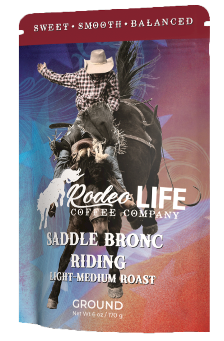 Saddle bronc rider gripping reins while horse bucks in rodeo arena