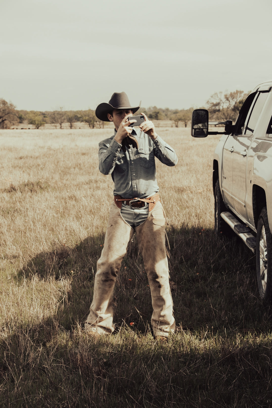 a man in a cowboy hat standing next to a truck