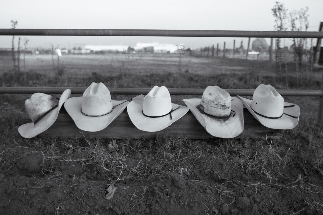 A row of cowboy hats sitting on top of a fence