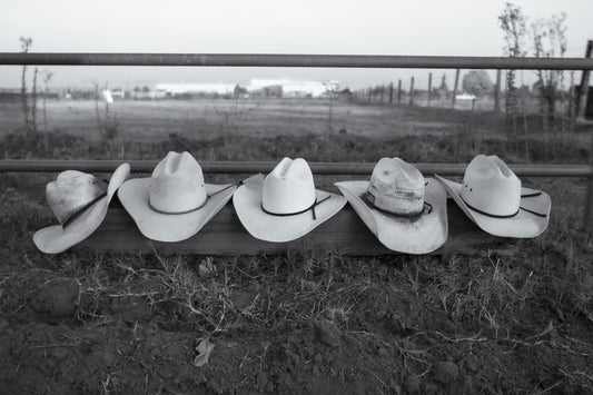 A row of cowboy hats sitting on top of a fence