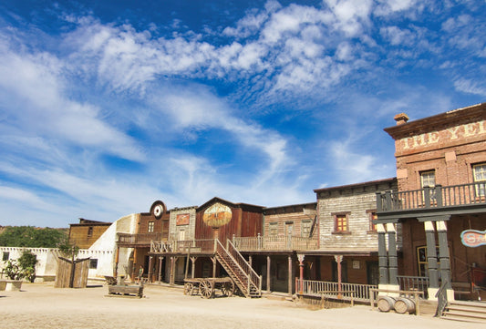 Old western town buildings under a blue sky.