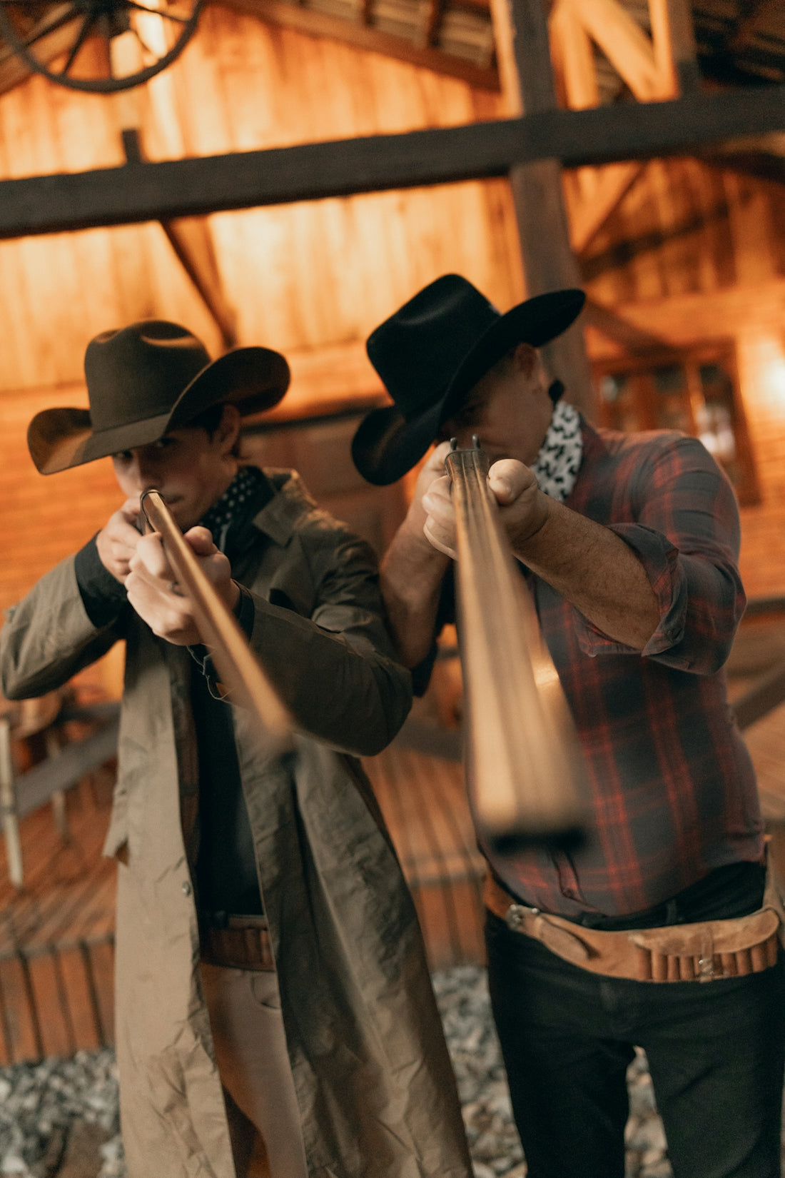 Two cowboys aiming rifles in a rustic building